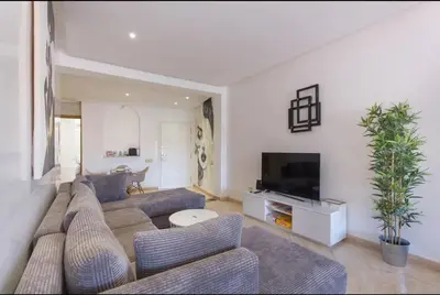a living room with a couch and a tv at Urban Chic 2 bedrooms in Utimate City Center in Marrakech