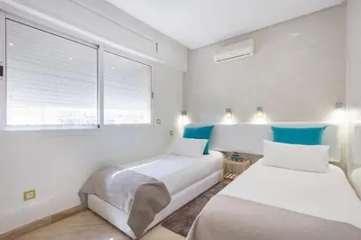 two beds in a white room with blue accents at Urban Chic 2 bedrooms in Utimate City Center in Marrakech