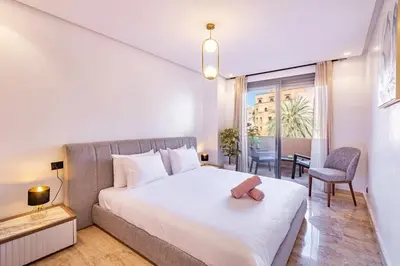 a bedroom with a large white bed and a chair at New 1BR appt in gueliz in Marrakech