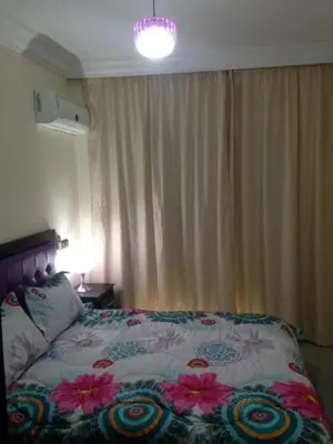 a bedroom with a bed with a flowered comforter and a lamp at Appartement Meublé Au Centre de Gueliz in Marrakech