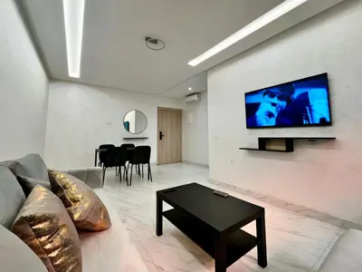 a living room with a couch and a tv on a wall at Appartement De Luxe Avec Piscine a Marrakech in Marrakech