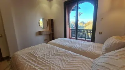 a bedroom with a bed and a window with a view at Marrakech Palmeraie 2 appt 2ch, résidence avec piscine in Marrakech