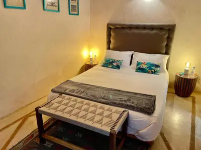 a bedroom with a bed with a bench on it at Riad Dom in Marrakech