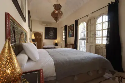 a bedroom with a large bed and two windows at Dar Lysis private with pool and breakfasts in Marrakech