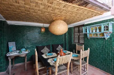 a dining room with a table and chairs and green tiles at Riad L'Hana, 3 ch, exclu medina in Marrakech