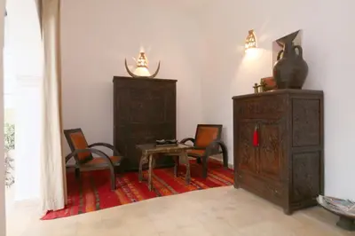 a room with two chairs and a table and a cabinet at Riad XCIX, basin, 3 bedrooms in Medina excluded in Marrakech