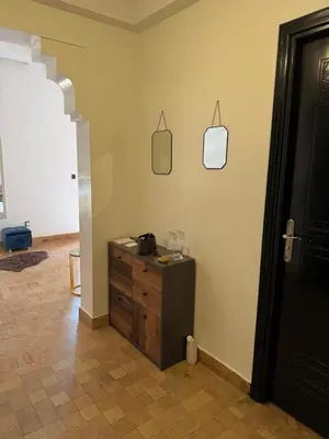 a room with a wooden dresser and a black door at Family apartement at Premium village in Marrakech