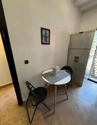 a room with a table and chairs and a refrigerator at Family apartement at Premium village in Marrakech