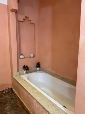 a bath tub in a bathroom with pink walls at Élégance Apartment with 5 swimming pool for family in Marrakech
