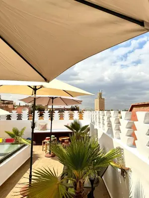 a balcony with tables and umbrellas on a building at Riad Nabil with Concierge and FREE Breakfast in Marrakech