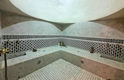 a bathroom with a tub with a tiled floor at Family villa pool sauna and hammam in Marrakech