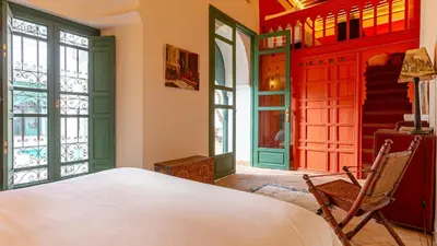 a bedroom with a bed and a chair and windows at Dar Salam Marrakech in Marrakech