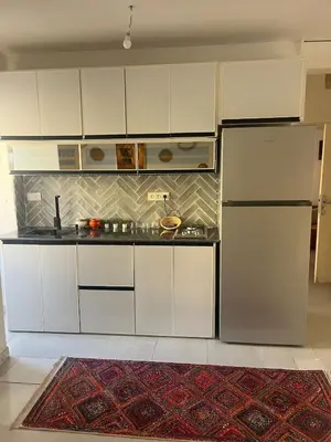 a kitchen with white cabinets and a refrigerator at Au cœur de la ville ocre in Marrakech