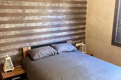 a bed in a bedroom with a wooden accent wall at Atlas Gardens Apartment in Sraghna
