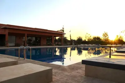 a swimming pool in front of a building at Atlas Gardens Apartment in Sraghna