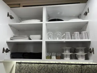 a white pantry with plates and dishes on shelves at Marrakech l'aéroport in Marrakech