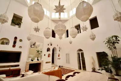 a large living room with white walls and chandeliers at Riad de charme in Marrakech