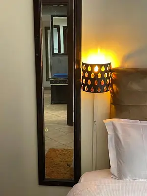 a bedroom with a mirror and a lamp next to a bed at Le grand jardin Marrakech in Marrakech