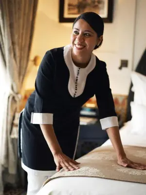 a woman making a bed in a hotel room at Place To Be Marrakech Downtown in Marrakech