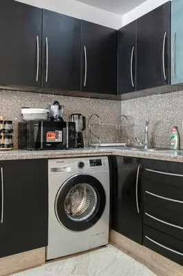 a washing machine in a kitchen with black cabinets at Place To Be Marrakech Downtown in Marrakech