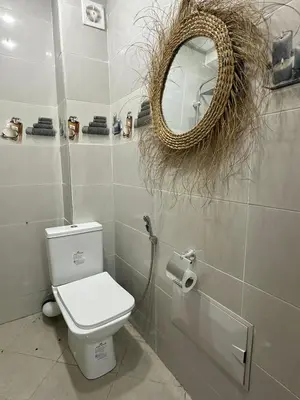 a white bathroom with a toilet and a mirror at appartement elegant in Marrakech
