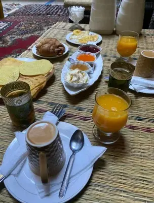 a table topped with plates of food and orange juice at Red Vibes Hostel Marrakech in Marrakech