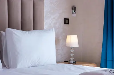 a bed with a white pillow and a lamp at 2BR Modern Apt 2min M Avenue Balcony Fiber WiFi 2 Pools 24 7 Security Hivernage in Marrakech