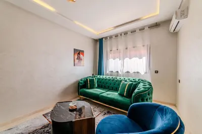 a living room with a green couch and a table at 2BR Modern Apt 2min M Avenue Balcony Fiber WiFi 2 Pools 24 7 Security Hivernage in Marrakech