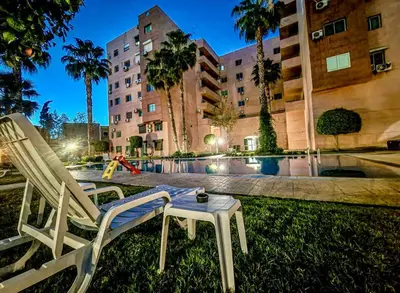 a table and chairs in the grass next to a pool at Apartment Msholidays 1 CH Marrakech pool in Marrakech