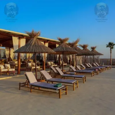 a row of lounge chairs and umbrellas on the beach at Quad Alia Marrakech in Marrakech
