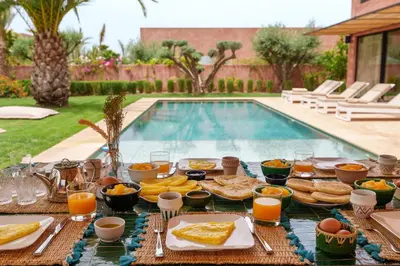 a table filled with food next to a swimming pool at Sublime Villa Neuve Marrakech - Piscine Chauffée in Marrakech