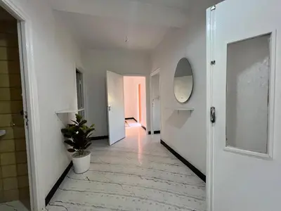 a hallway with white walls and a mirror and a plant at Résidence zitouna in Marrakech