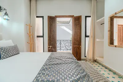 a bedroom with a bed and a door to a balcony at Riad Dar Amarena Exclusif BreakFast in Marrakech