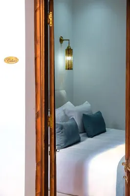 a bedroom with a white bed with blue pillows at Riad Dar Amarena Exclusif BreakFast in Marrakech