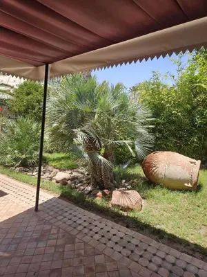 an umbrella over a garden with a palm tree at Eden Lodges & SPA-Boutique Hôtel de Luxe in Marrakech