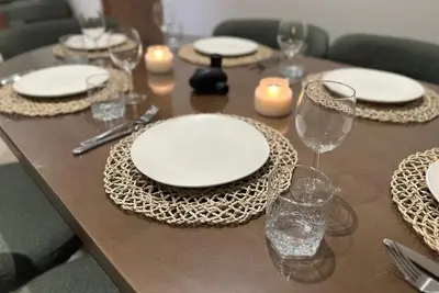 a wooden table with white plates and glasses and candles at Prestige cocon in Marrakech