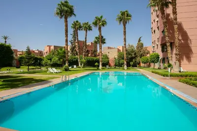 a large swimming pool with palm trees and a building at Artisan's Hideaway Marrakech in Marrakech