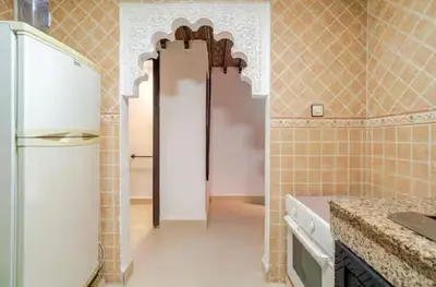 a kitchen with a white refrigerator and a tile wall at Riad Amani in Marrakech