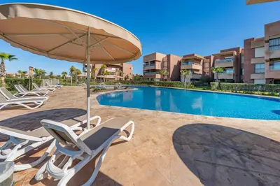 a swimming pool with lounge chairs and an umbrella at Luxury Saphir- Golf, piscines & calme in Marrakech
