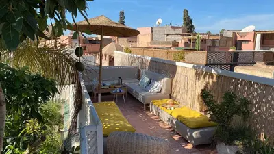 a rooftop patio with couches and an umbrella at Dar Z5 3 bedrooms in Marrakech
