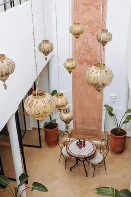 a room with a table and chairs and chandeliers at Riad de charme avec piscine rooftop in Marrakech