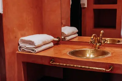 a bathroom with a sink and a mirror and towels at Riad de charme avec piscine rooftop in Marrakech