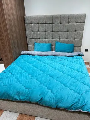 a bed with a blue comforter and blue pillows at Aéroport, Appartement in Marrakech