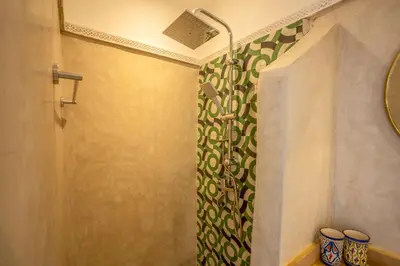 a shower with a green and white shower curtain at Riad Ilyan & Spa in Marrakech