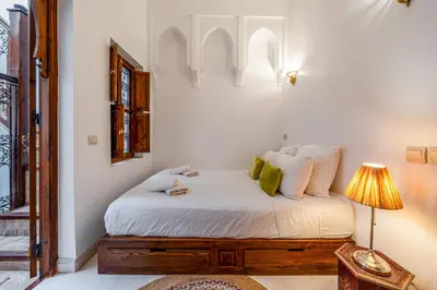 a bedroom with a bed with a table and a lamp at L'Alchimiste - Riad Entier à 10 minutes Jemaa El Fna in Marrakech