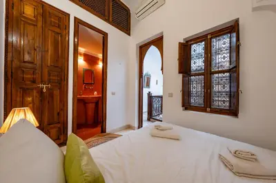 a bedroom with a bed and a window and a door at L'Alchimiste - Riad Entier à 10 minutes Jemaa El Fna in Marrakech
