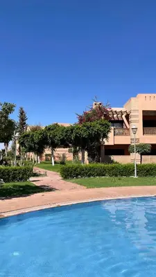 a blue swimming pool in front of a building at Marrakech Apartment with garden Marrakech in Marrakech