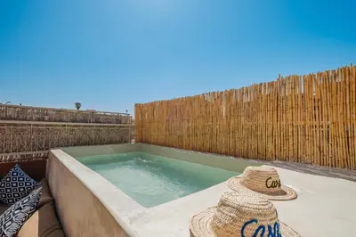 a swimming pool with two hats on a patio at Maison 3 chambre avec bassin chauffée centre ville Gueliz in Marrakech
