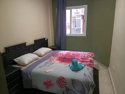 a bedroom with a bed with a floral bedspread and a window at family apartment 06 in Marrakech