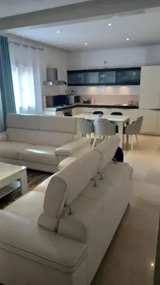 a living room with white furniture and a kitchen at Appartement centre Marrakech in Marrakech
